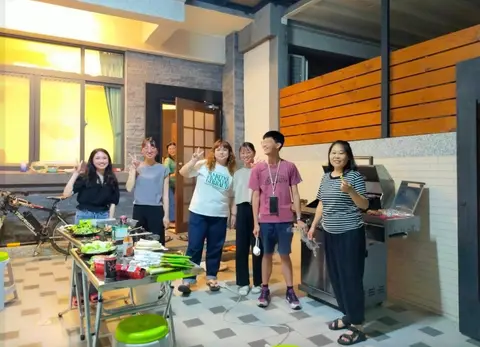戶外烤肉爐邊一群朋友圍著備料桌