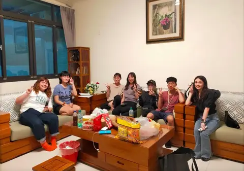 客廳沙發上一群人聊天唱歌、桌上擺滿零食